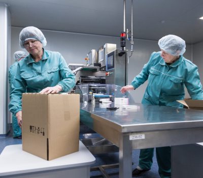 Pharmaceutical technicians work in sterile working conditions at pharmaceutical factory. Scientists wearing protective clothing